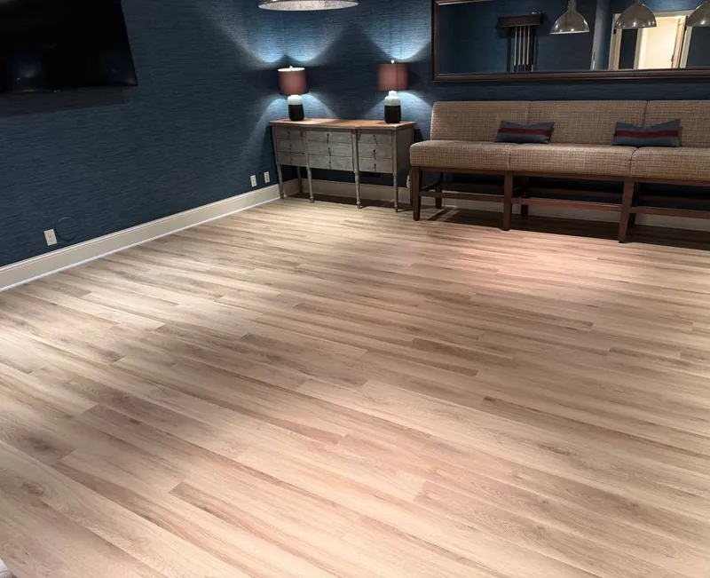 Light oak-look luxury vinyl plank installed in a lower-level family room with navy walls, installed by Anton's Floorcovering