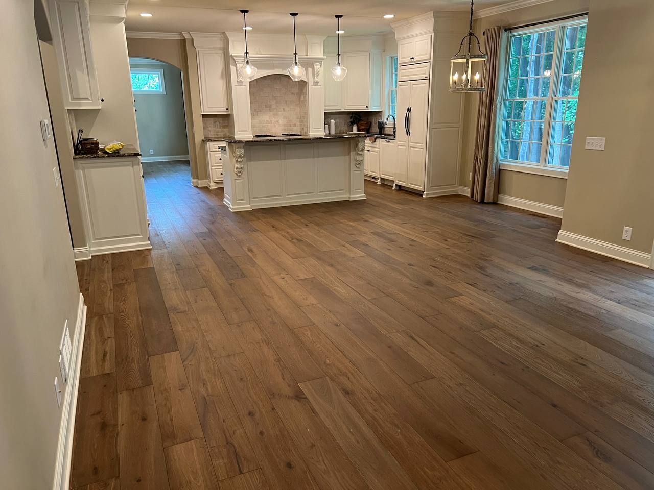 Kitchen and living area with medium brown hardwood plank flooring and white cabinetry.