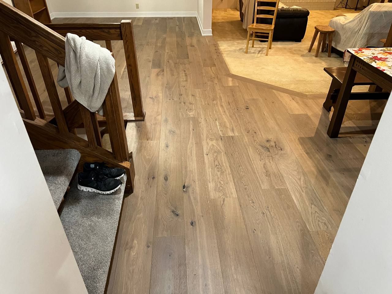 Medium-toned hardwood plank flooring installed in a living room with furniture and entryway visible.