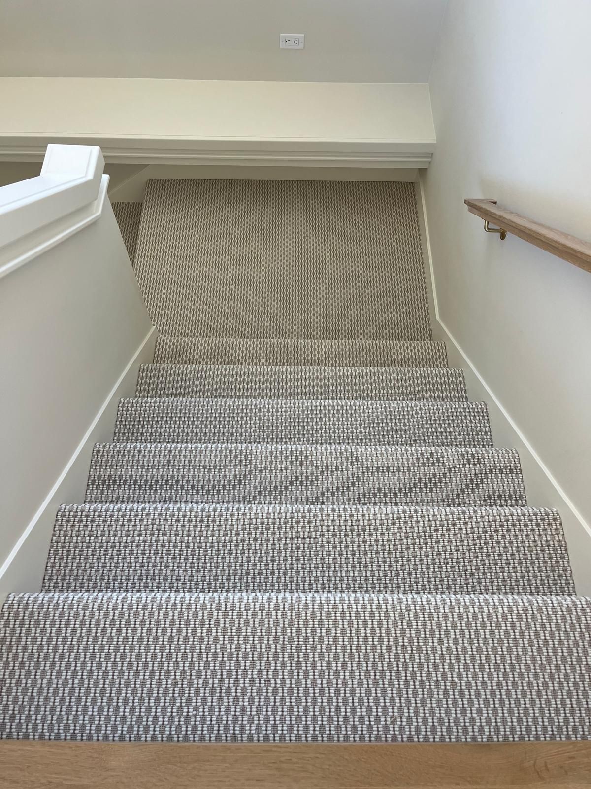 Staircase with gray and white textured carpet and white painted trim.