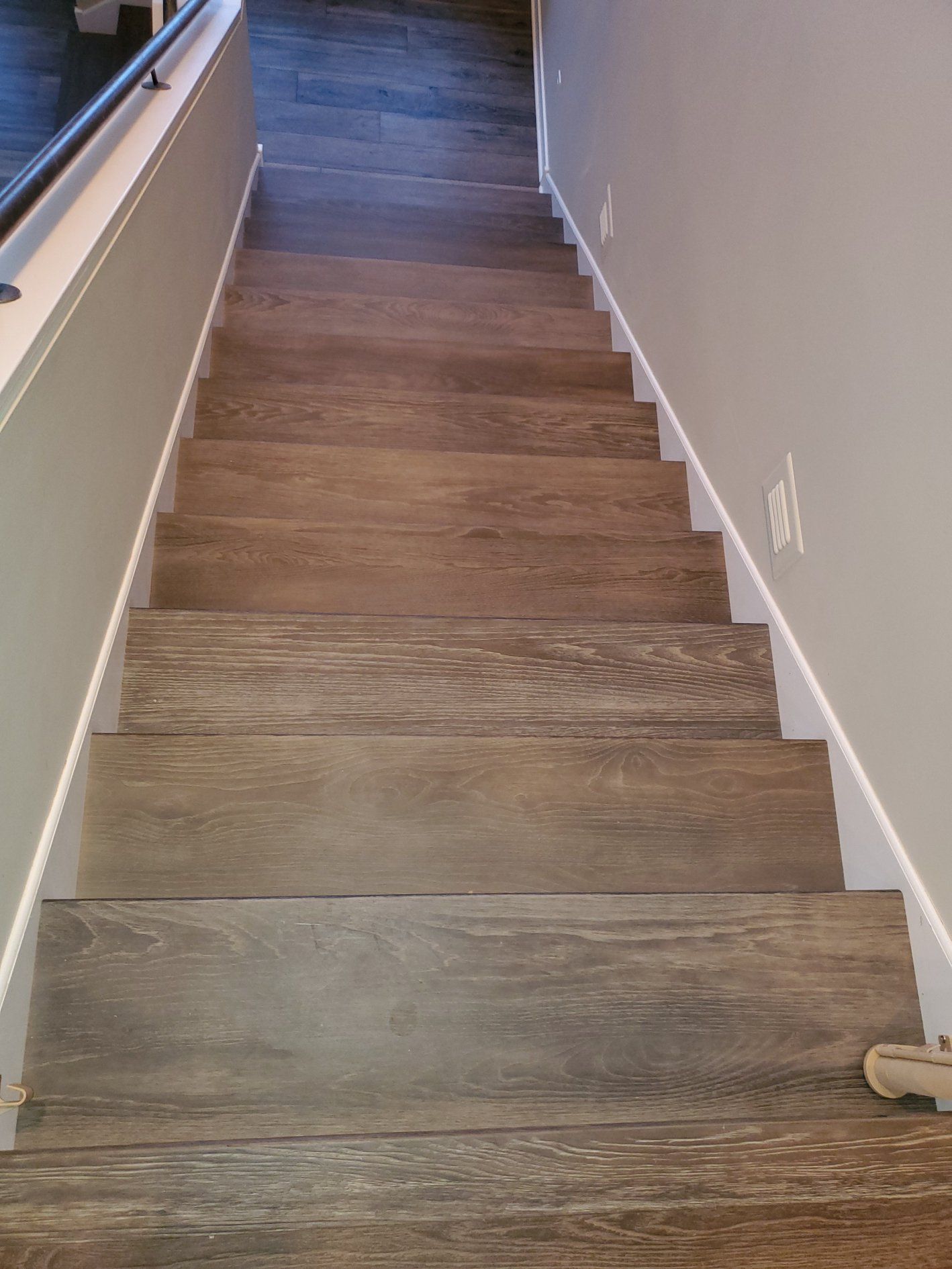 Hardwood plank stairs with white risers installed in a residential staircase.