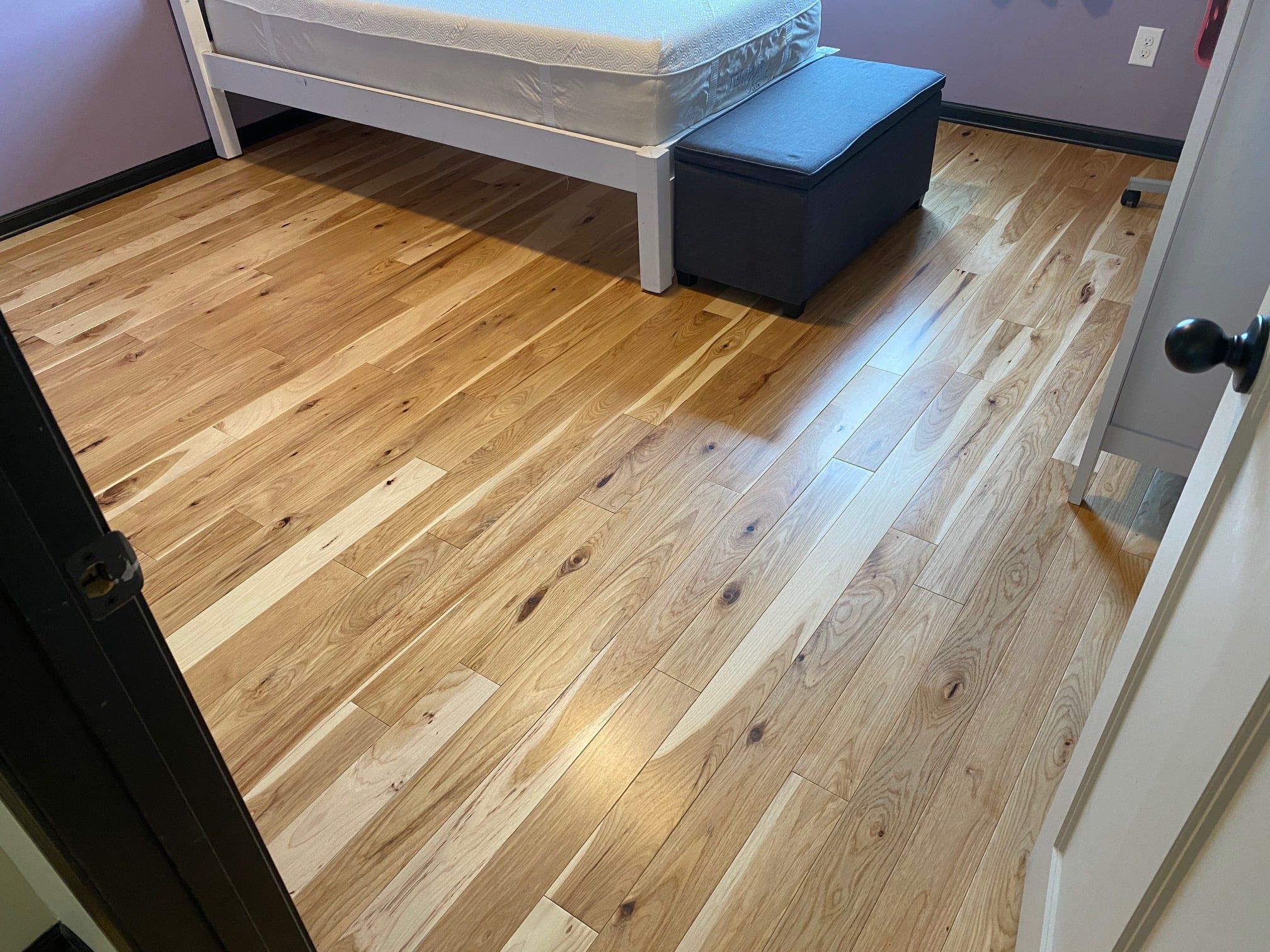 Hickory hardwood plank flooring installed in a bedroom with medium finish and natural grain patterns.