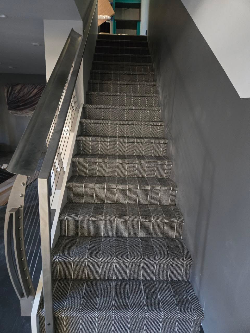 Carpeted staircase with gray and brown plaid pattern and white railings in an indoor residential setting.