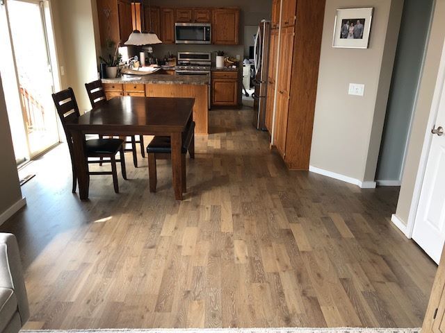 Medium-tone oak hardwood plank flooring installed in a kitchen and dining area with wood cabinetry.