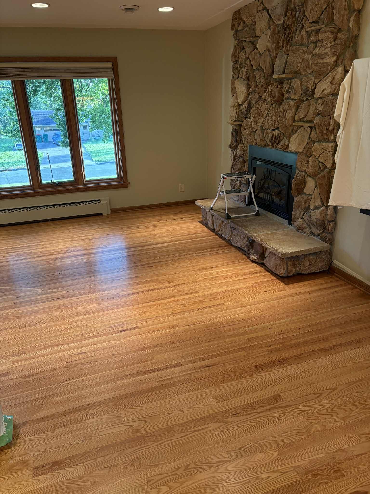 Red oak hardwood floor installation in a living room with fireplace and large windows.
