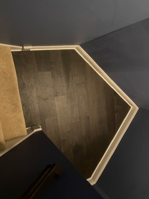 Hardwood plank flooring with medium brown finish installed in a room with white trim and gray walls.
