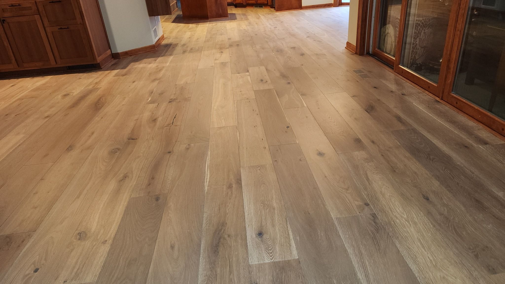 Wide plank hardwood hallway with medium tan and gray tones and natural knot details.