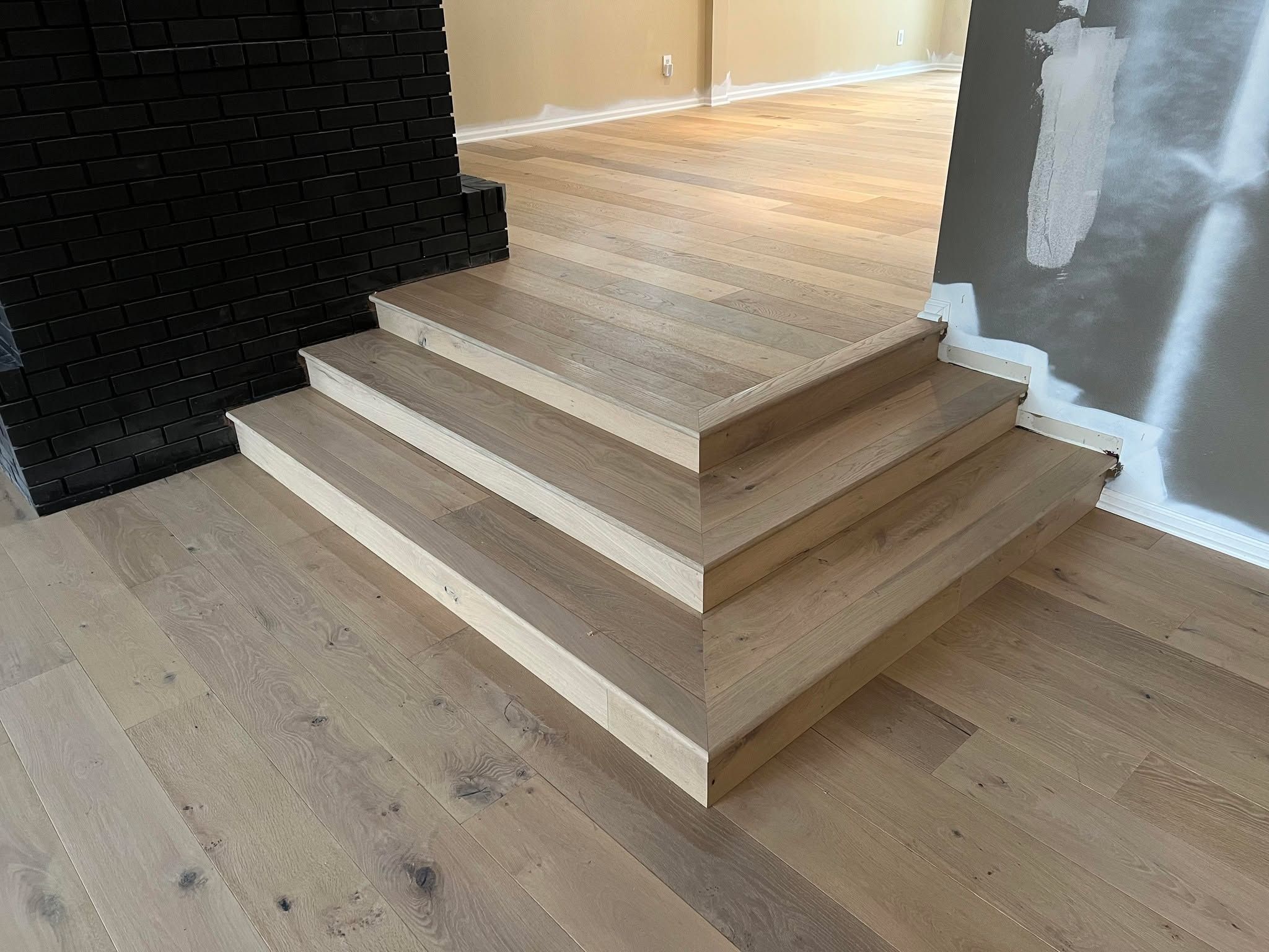 Newly installed hardwood flooring with a multi-level staircase transition during construction.