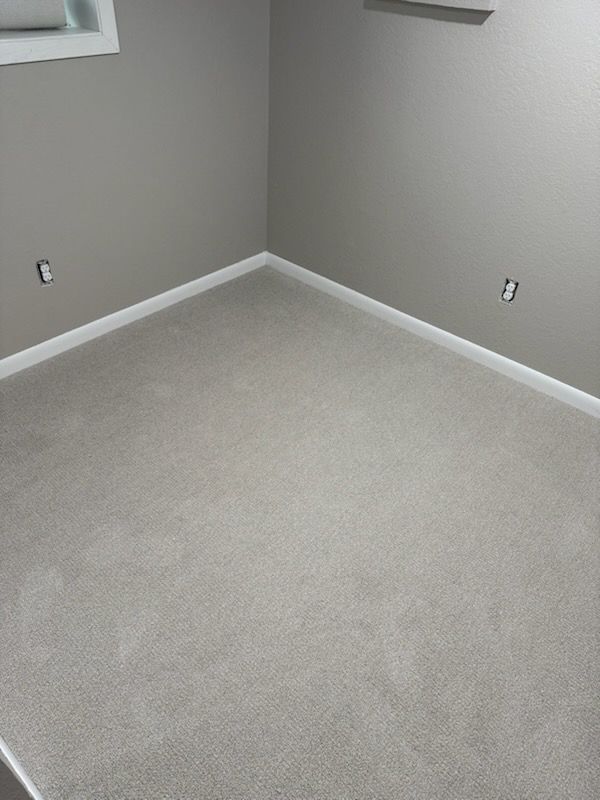 Light gray carpet installed in a bedroom corner with white baseboards and newly framed electrical outlets.