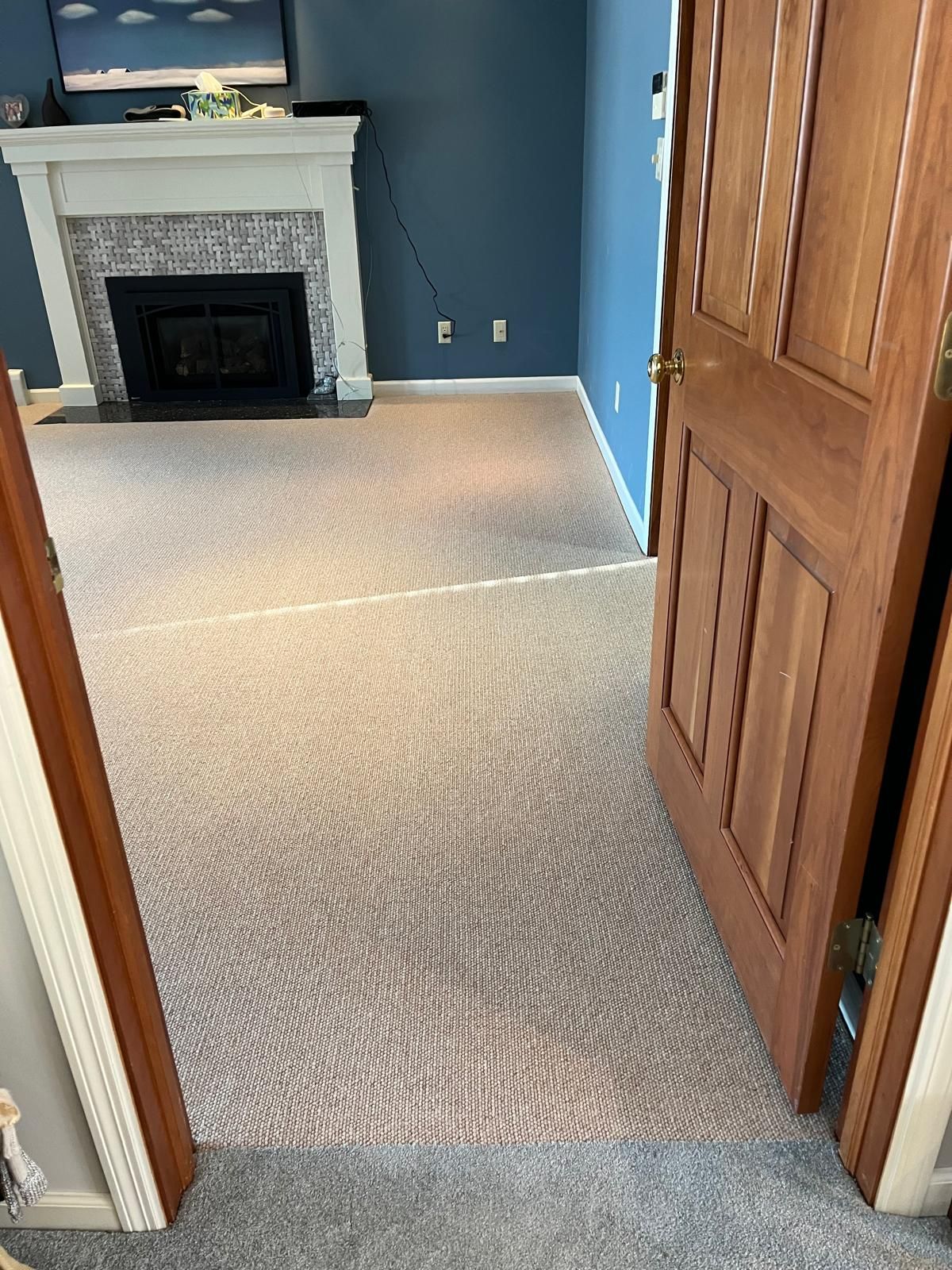 Light beige wool carpet installed in living room with fireplace and blue accent wall.