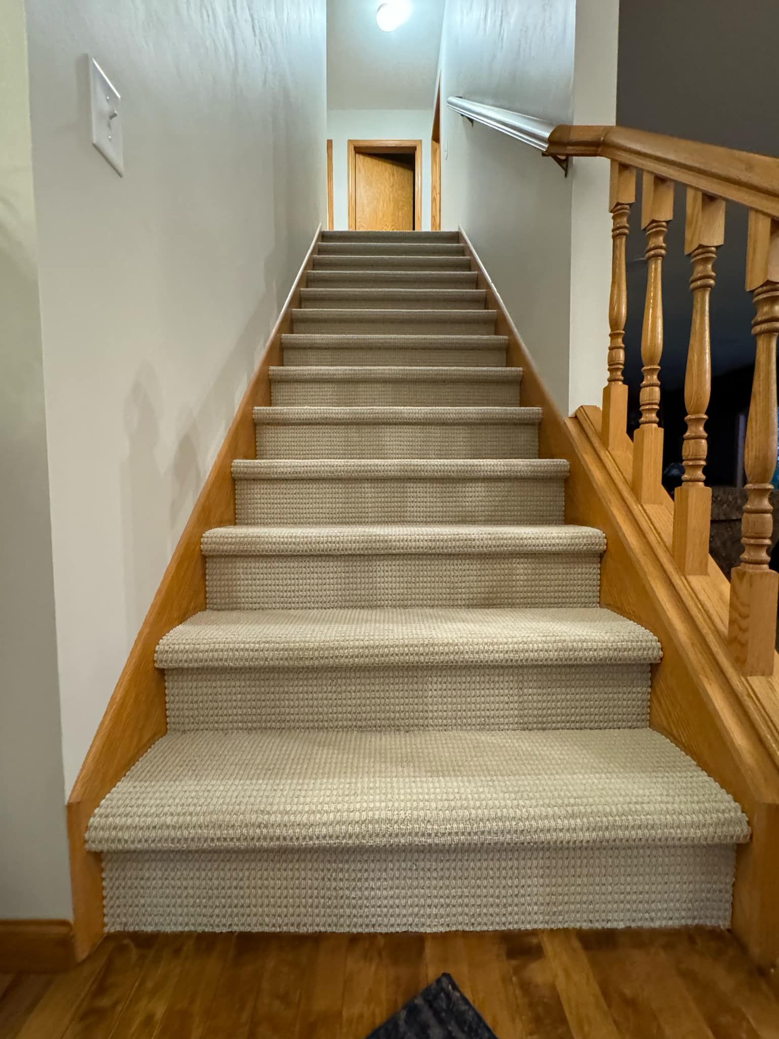 Carpet installed on staircase with wooden railings and trim.