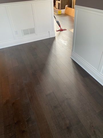 Dark hardwood plank flooring installed in a hallway with white baseboards and trim.