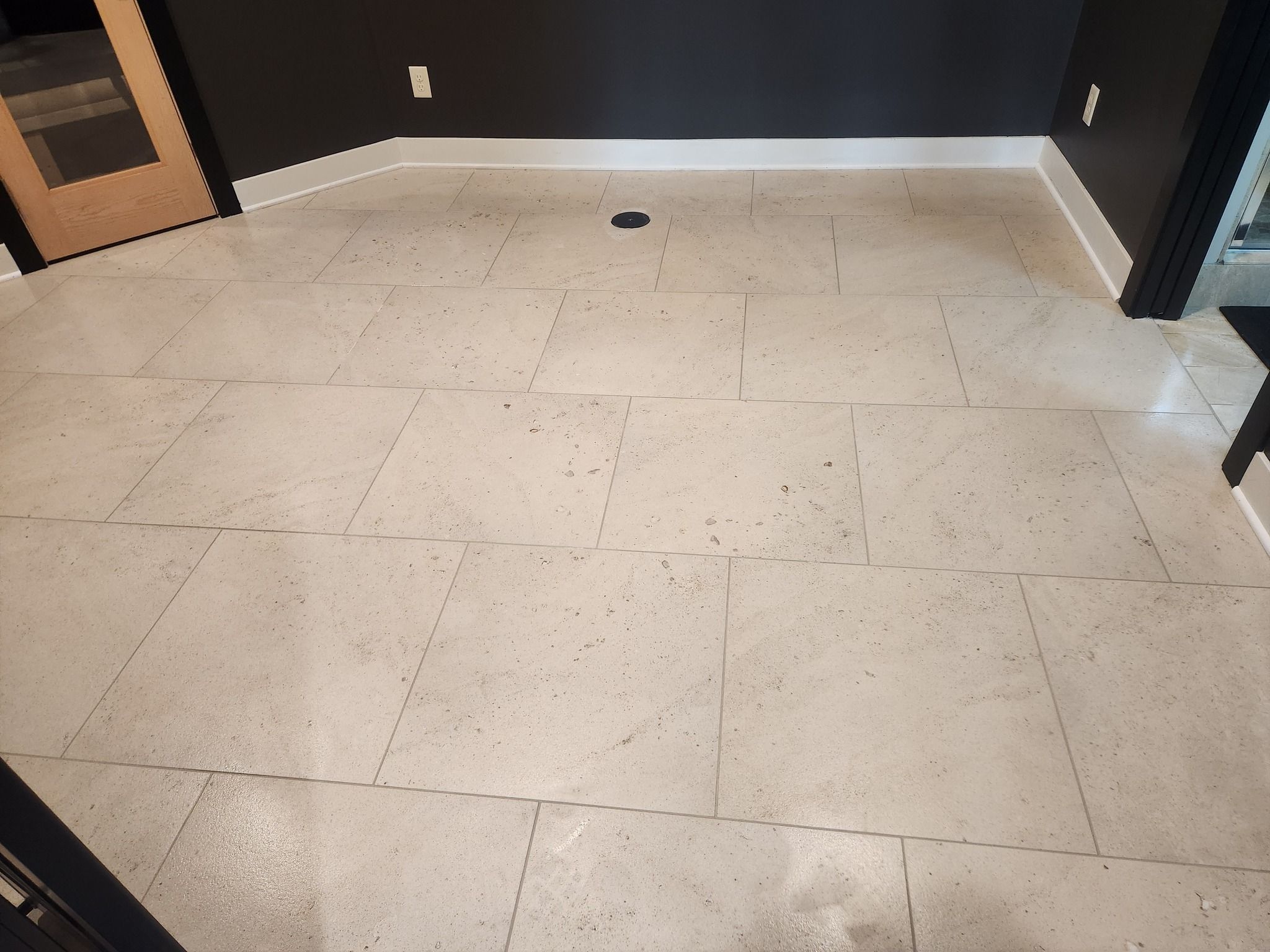 Light beige tile floor with large square tiles and visible grout lines in a sauna room.