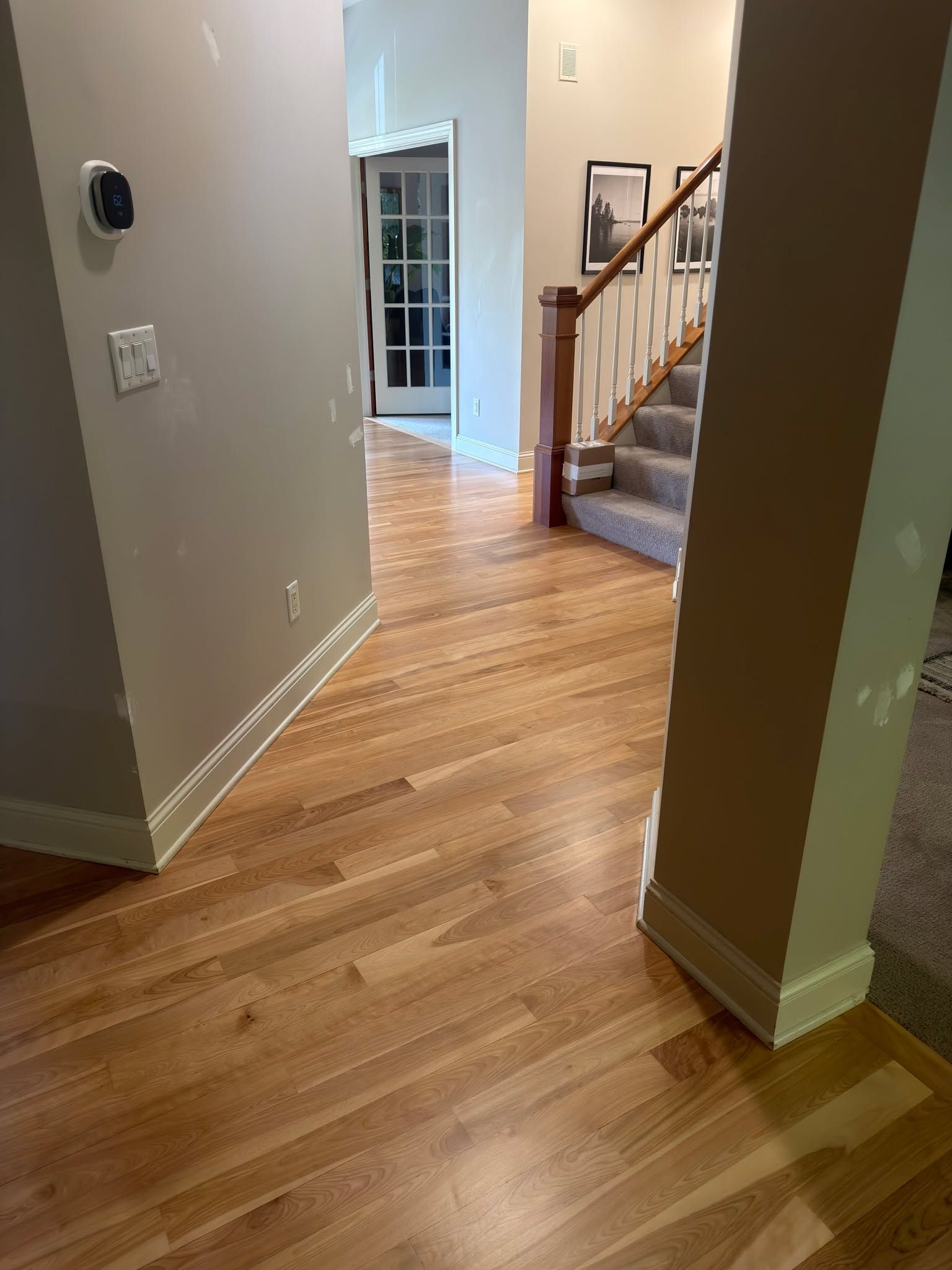 Hallway with refinished red birch hardwood flooring and stairs visible in background.