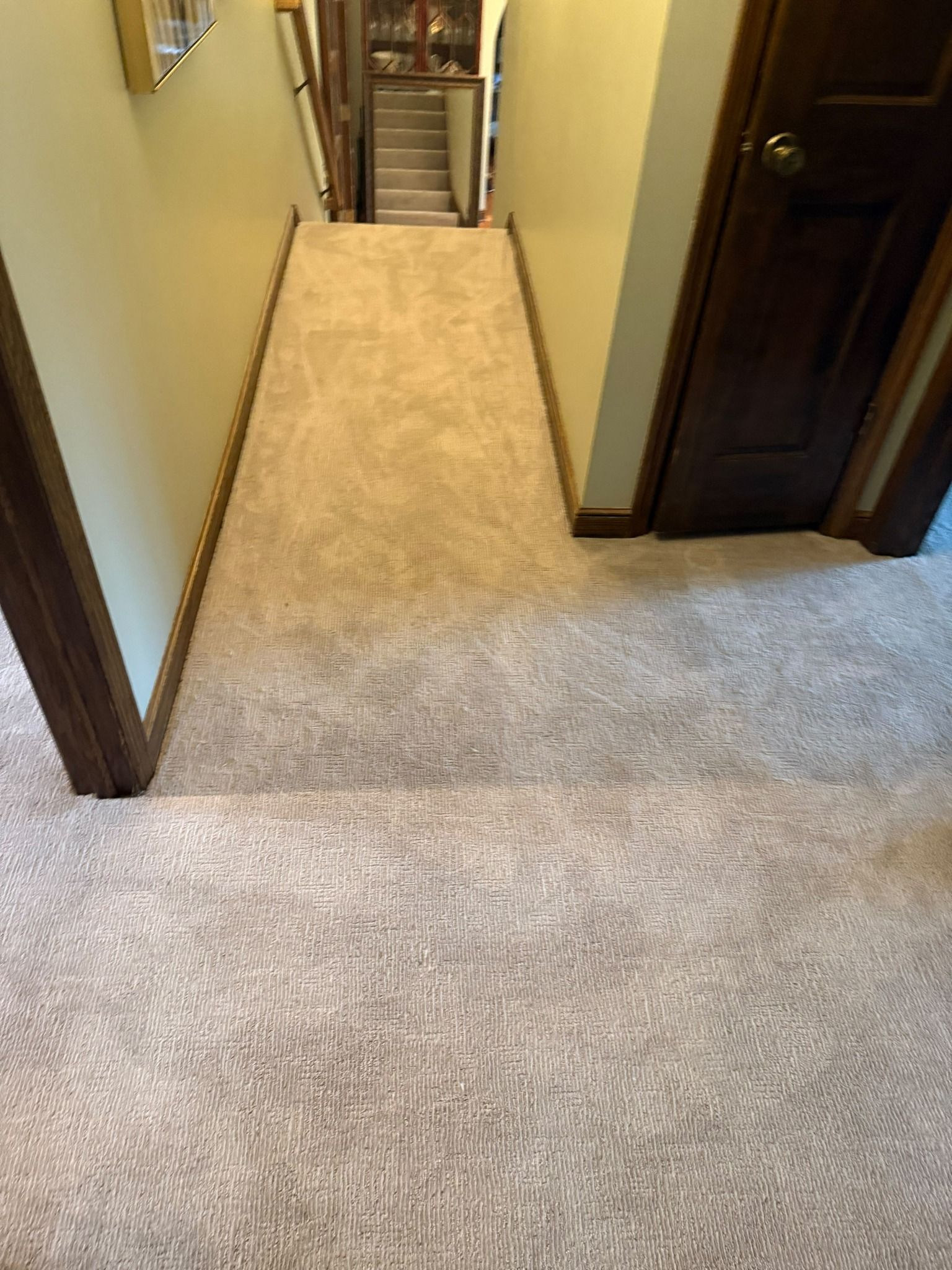 Hallway with light tan carpet and dark wood-framed doorways leading to stairs.