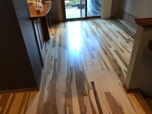 Light multi-toned hickory hardwood flooring with random width planks in an open living area.