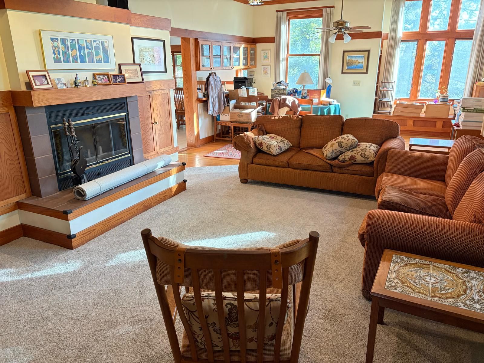 Beige carpet in a living room with a fireplace, wood paneling, and brown upholstered furniture.