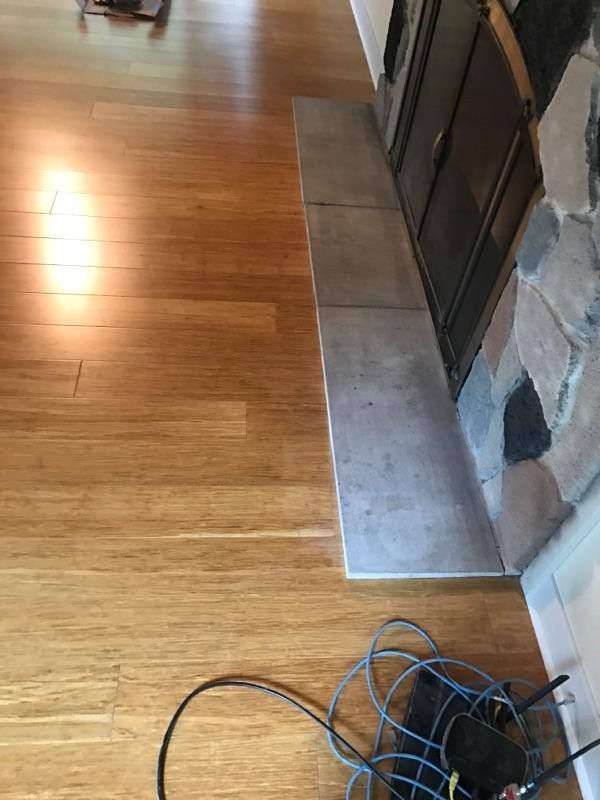Golden-brown hardwood plank flooring installed in kitchen with transition strip at doorway.