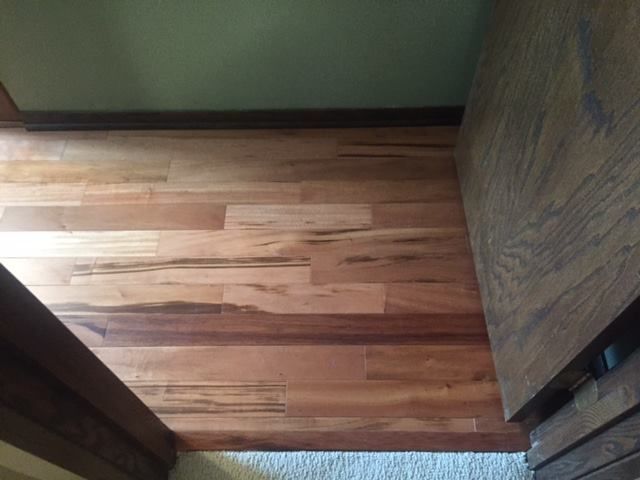 Engineered hardwood plank flooring in varied widths with natural grain in a hallway.