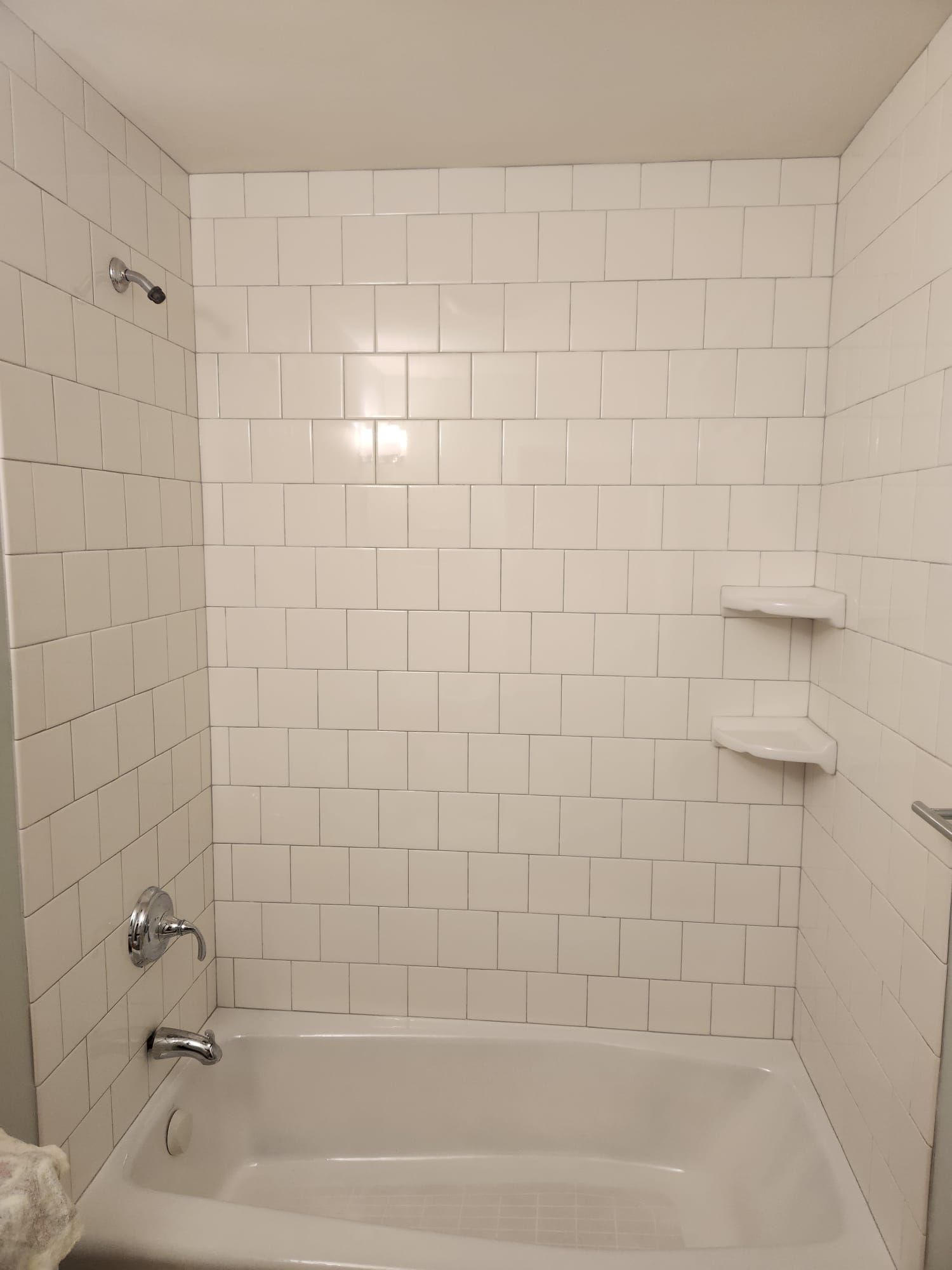 Bathroom with white subway tile tub surround, shelving, and updated fixtures.