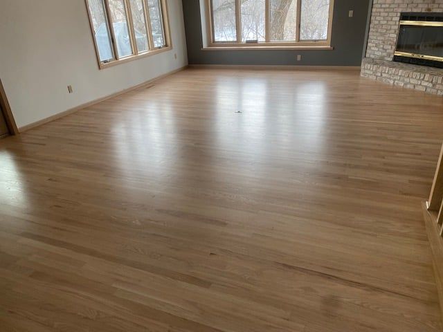 Refinished red oak hardwood flooring in a living room with fireplace and windows.