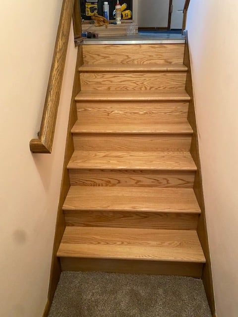 Hardwood stair treads and risers with wood handrail in residential staircase.