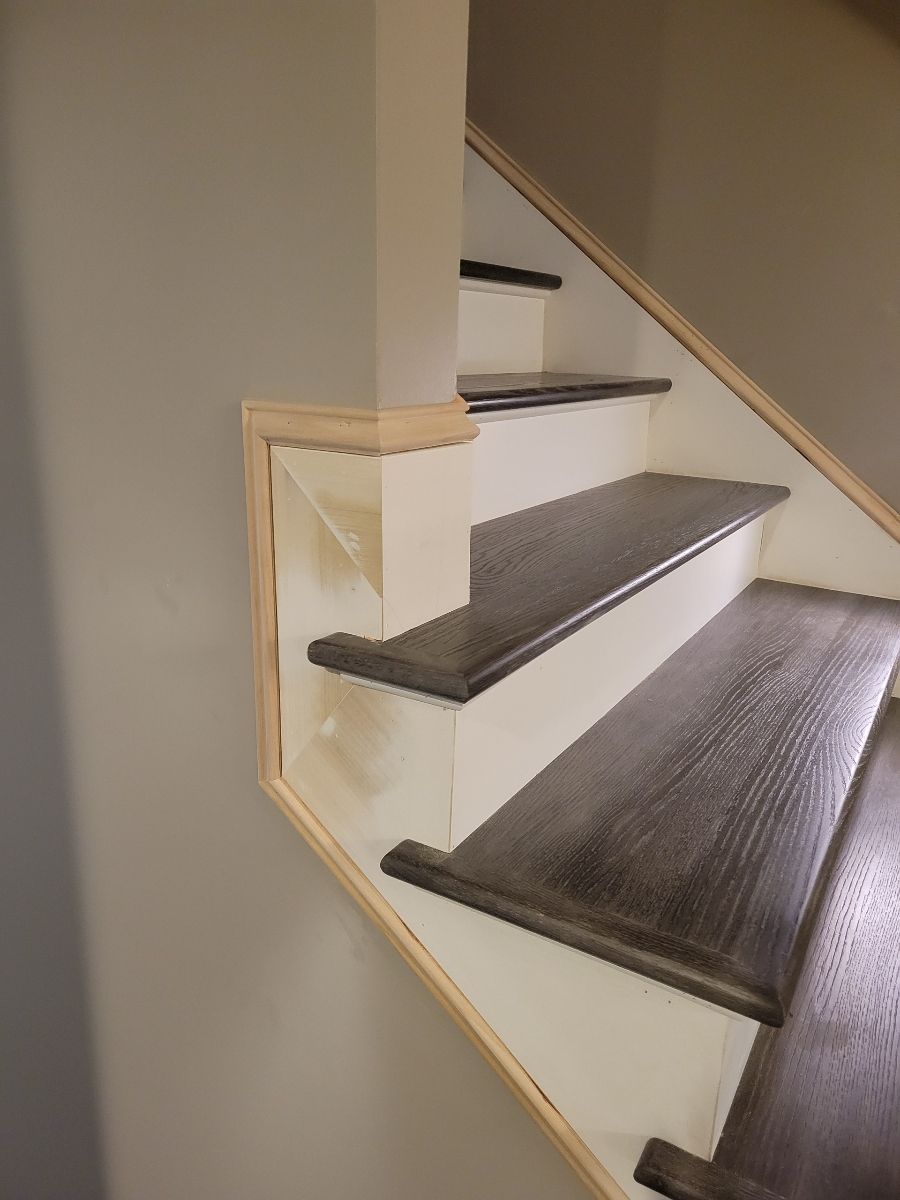 Staircase with dark hardwood treads, white risers, and metal edge nosing.