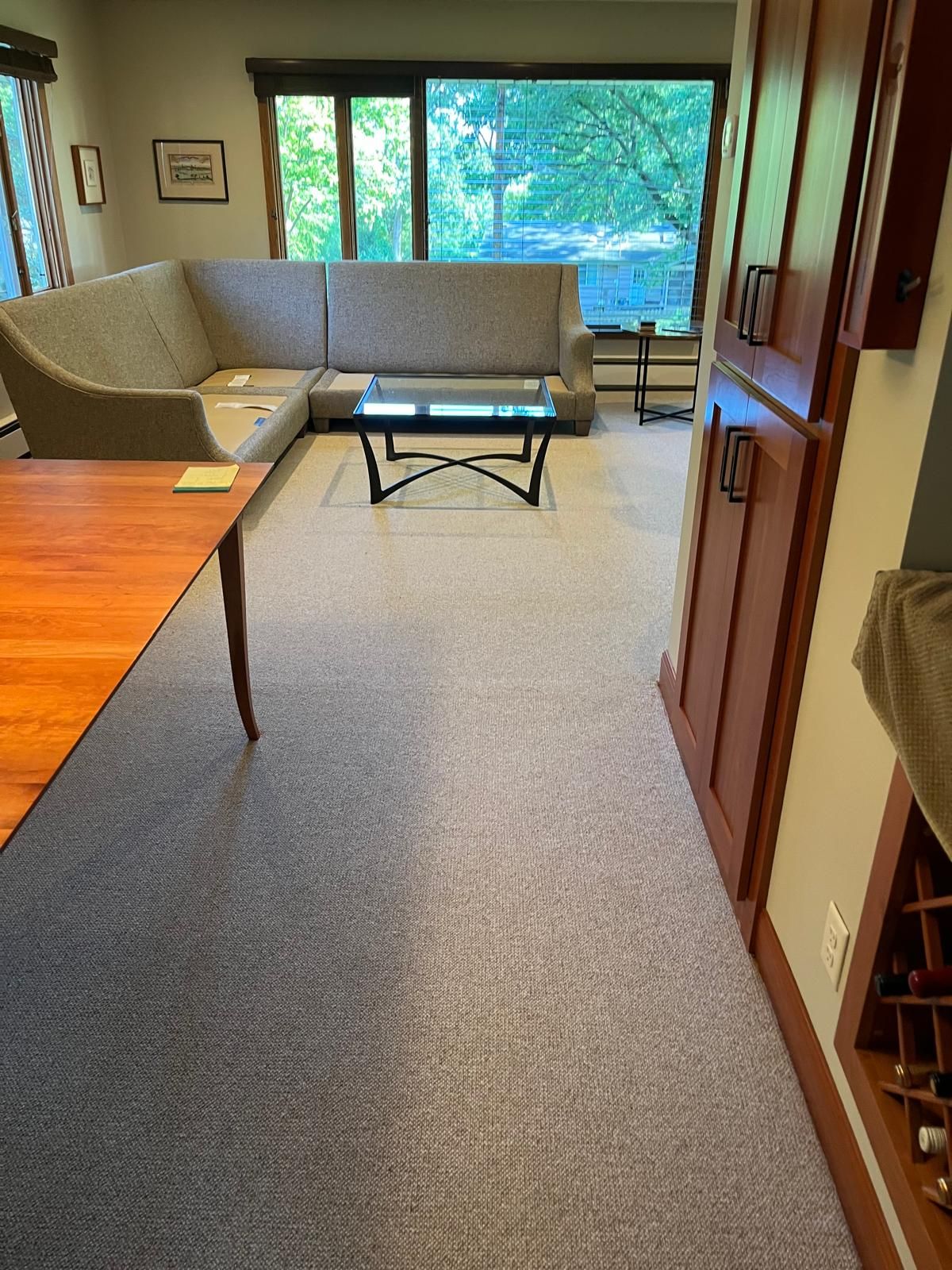 New gray wool carpet installed in a living room with wood flooring visible in an adjacent area.