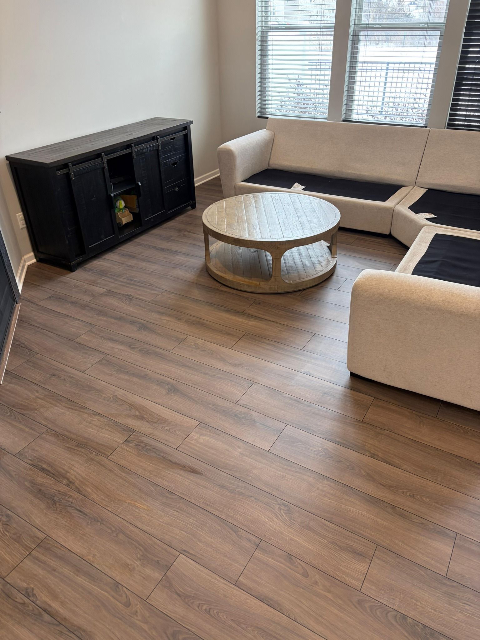 Laminate plank flooring in medium brown tones installed in a living room with modern furniture.